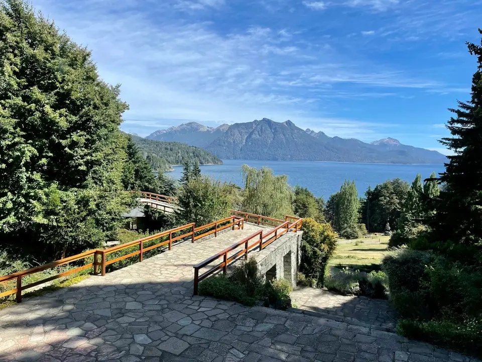a stone walkway leading to a lake with mountains in the background — Bariloche