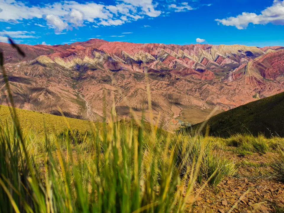 a view of a mountain range with grass in the foreground — Quebrada de Humahuaca