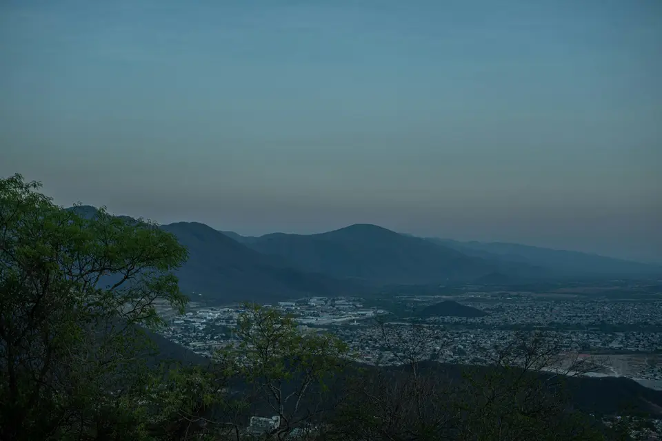 Distant city nestled among rolling hills at dusk — Salta