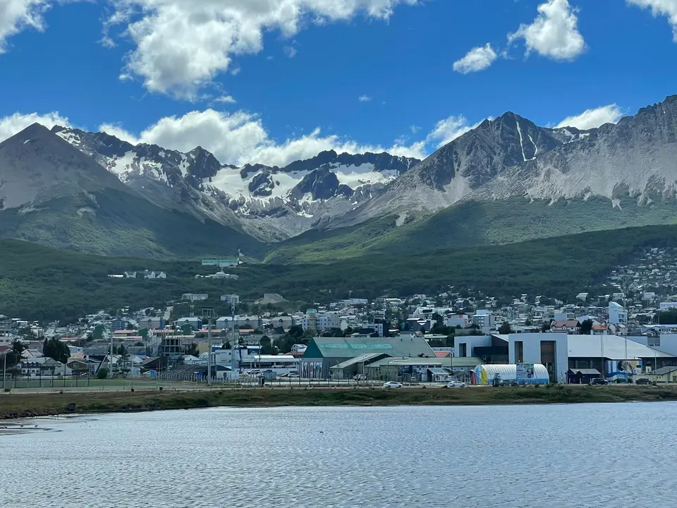 a town by a lake with mountains in the background — Ushuaia