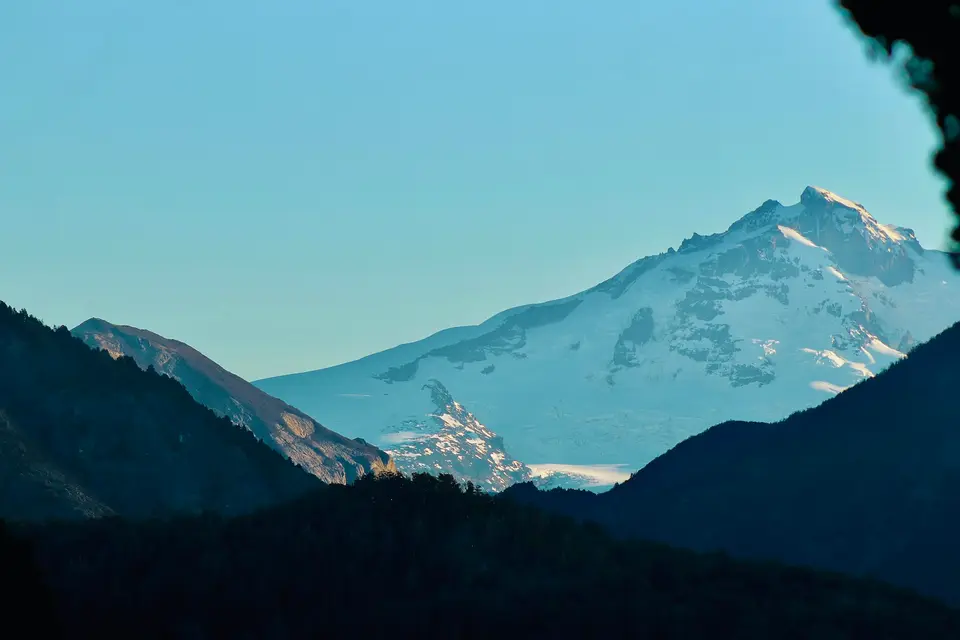 Distant snow-capped mountains framed by dark foreground peaks — Valle de Uco