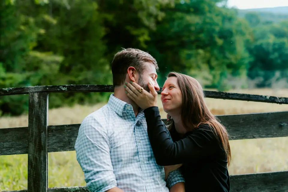 Couple embraces near a rustic wooden fence outdoors